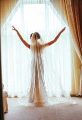 Portrait of the beautiful bride against a window indoors