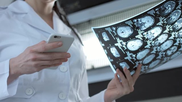 Female doctor viewing mri scan and chatting online via smart phone