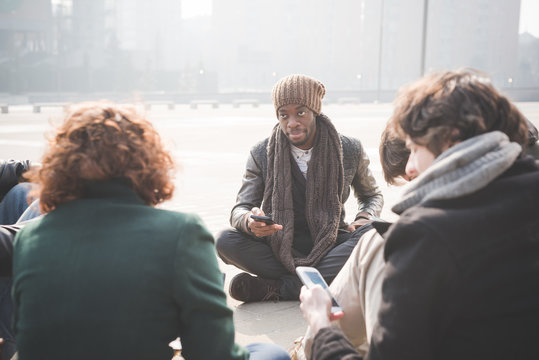 Young adult friends sitting networking on smartphones