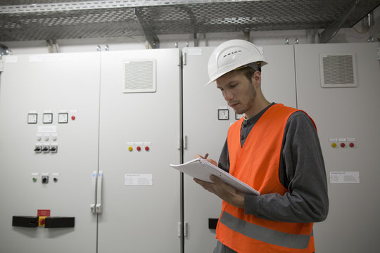 Young male engineer reading paperwork in technical room