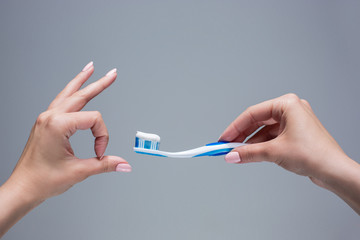 Toothbrush in woman's hands on gray