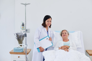 Portrait of nurse and senior female patient in bed