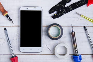 smartphone and equipment repair on the white wooden background.