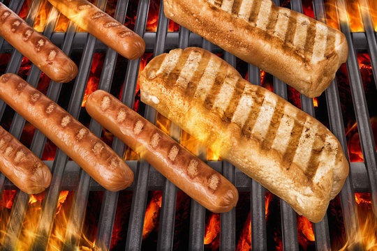 Sausages and hot dog buns over a hot barbecue grill.
