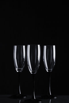 Three clear champagne glasses on a black background