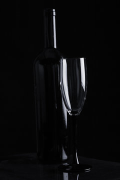 Champagne glass in front of black bottle
