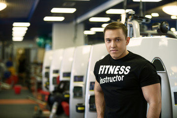 Fitness guy posing on backdrop of sports equipment