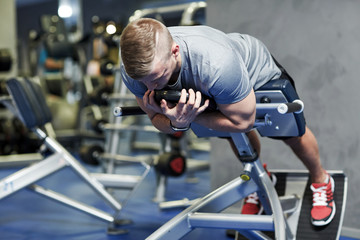 Fototapeta na wymiar young man flexing back muscles on bench in gym
