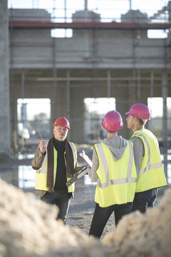Architect explaining to builders on construction site