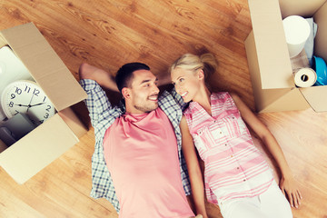 happy couple lying on floor among cardboard boxes