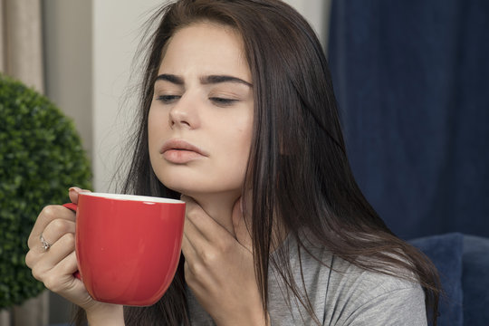 Young Woman With A Sore Throat Drinking Tea.