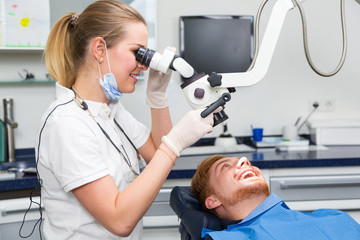 Dentist examining patient's teeth using a microscope