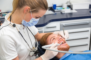 Dentist treats patient's teeth with a dental drill