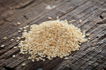 A heap of raw sesame seeds, on wooden surface.
