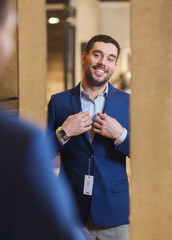man trying jacket on at mirror in clothing store