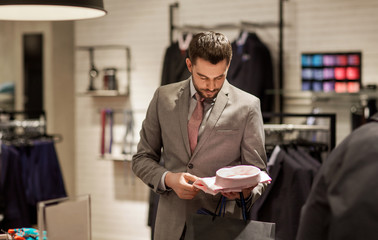 happy young man choosing shirt in clothing store