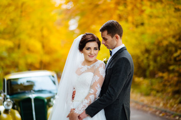 Happy stylish couple kissing in old city with old cars