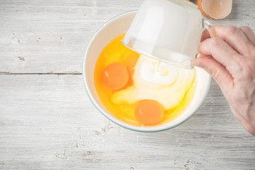 Mixing eggs and yogurt in the ceramic bowl top view