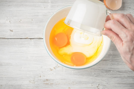 Mixing eggs and yogurt in the ceramic bowl top view