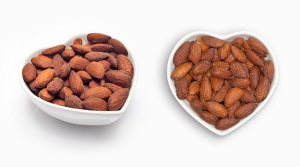 Almonds in a heart shaped bowl, isolated on white