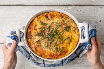 Moussaka with rosemary in the ceramic pan in the hand top view