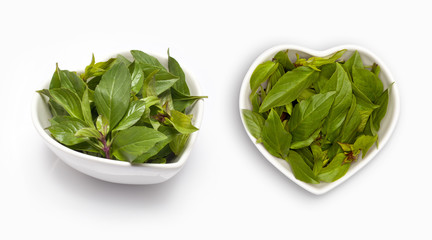 Basil leaves  in a heart shaped bowl, isolated on white