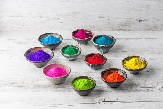 Ceramic Cups With Colorful Holi Powder On White Wooden Table With Copy Space