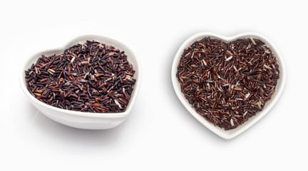 Brown rice in a heart shaped bowl, isolated on white