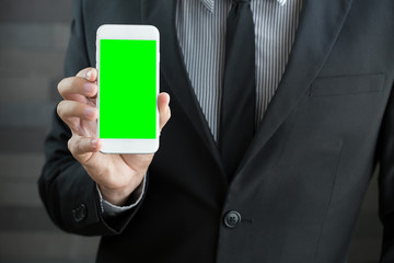 Businessman holding mobile smart phone with green screen