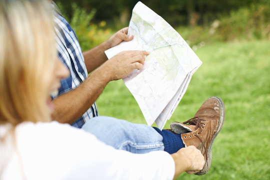 Couple Putting On Walking Shoes, Map Reading And Preparing For Walk