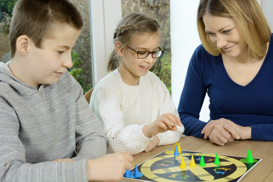 Frau und Kinder spielen Brettspiel als Gesellshaftsspiel