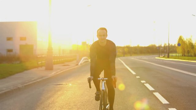 Man riding fixed gear bike on the road at sunset