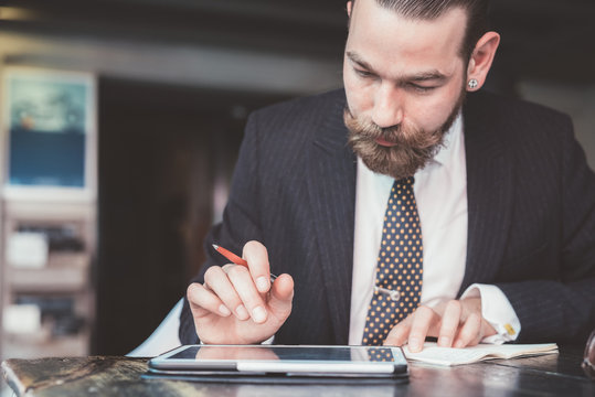 Businessman making diary notes from digital tablet at cafe table