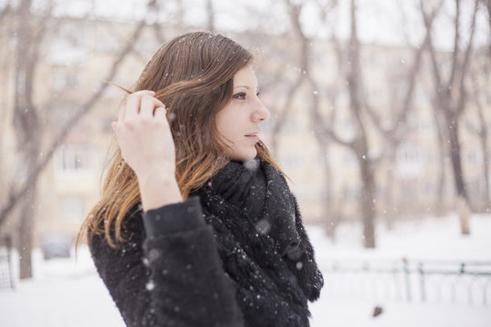 Young woman playing with her hair, wintry background