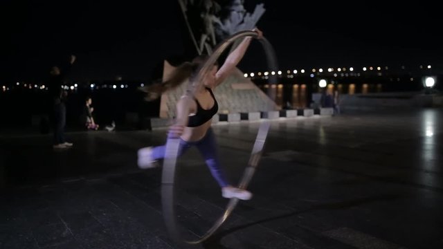 Woman on cyr wheel in city lights