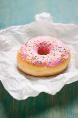 Fresh sweet colorful homemade pink donut on a green wooden vintage background for birthday or party, closeup, selective focus