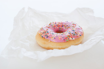 Fresh sweet colorful homemade pink donut on a white kitchen background for birthday or party, closeup, selective focus
