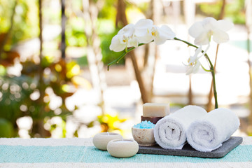 Spa and wellness massage setting Still life with candle, towel and stones Outdoor summer background