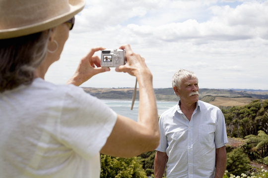 Wife photographing husband, ocean in background, Raglan, New Zealand