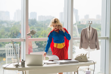 Powerful superwoman talking on phone and working with documents  in office