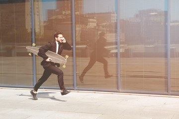 Fototapeta na wymiar Hurrying to work. Toned picture of full length of young businessman looking forward while running along street and speaking over mobile phone.