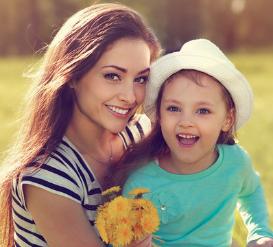 Beautiful smiling mother embracing her cute daughter with yellow