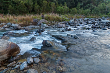 Fototapeta na wymiar River water flowing through rocks at dawn