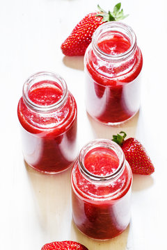 Strawberry smoothie in bottles on a white wooden background, top
