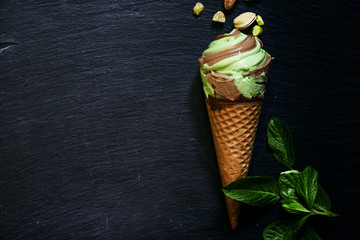 Mint pistachio ice cream with chocolate in waffle cone, scattere
