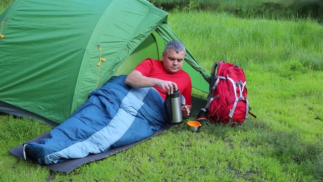 A man sitting near tent and talking on the phone.