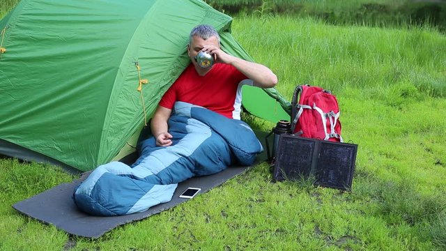 A man sitting near tent and talking on the phone.