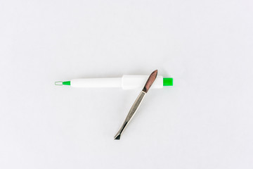 Tick remover and steel tweezers on white background, studio shot. 