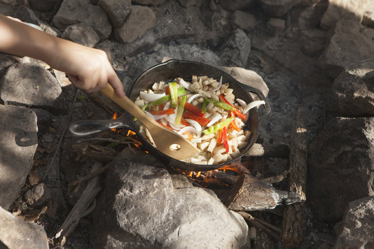 Hand of teenage boy cooking stir fry on campfire, Indiahoma, Oklahoma, USA