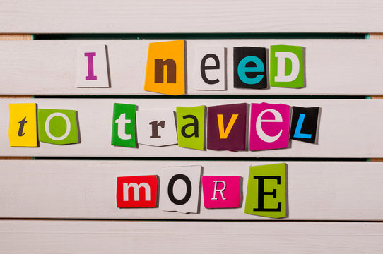 I need to travel more - written with color magazine letter clippings on wooden board. Concept  image
